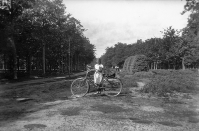 805421 Afbeelding van een jonge Mary Balfour van Burleigh naast haar fiets in de omgeving van de pyramide van ...